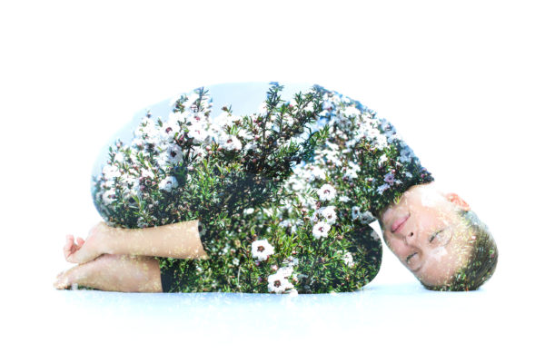 Double exposure of a young woman performing yoga asana, combined with photograph of nature