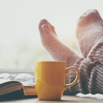 Woman,Resting,Keeping,Legs,In,Warm,Socks,On,Table,With