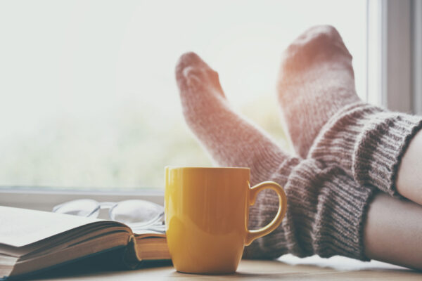 Woman,Resting,Keeping,Legs,In,Warm,Socks,On,Table,With